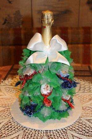 للزينة ، يمكنه استخدام الحلوى التي يمكن لصقها مع الفراغات. اصنع قوسًا من شريط الساتان وزين الزجاجة. شجرة عيد الميلاد مصنوعة من الشمبانيا والحلويات جاهزة.