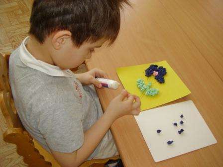 Derefter skal dit barn tegne en form for figur eller sammensætning på et kartonark og derefter begynde at fylde det med kugler fra servietter.